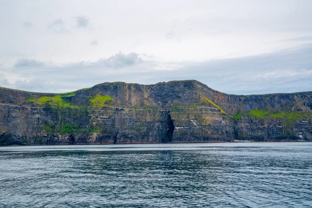 udsigt over sea cave nær Cliffs of Moher, der blev brugt ved filmoptagelse af Harry Potter og Halvblodsprinsen, set fra vandet på en overskyet dag.