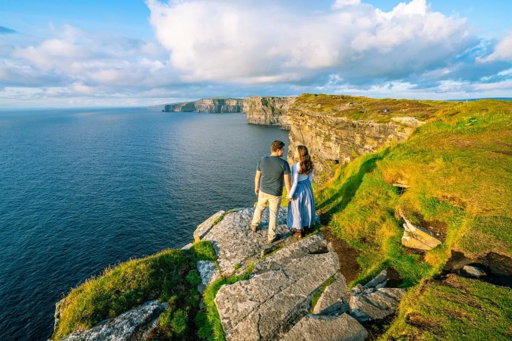 Kate Storm and Jeremy Storm standing in front of the Cliffs of Moher in Ireland shortly before sunset