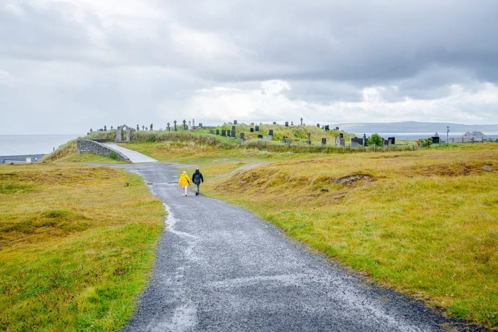 Couple in the distance walking down an empty road on Inisheer Island that leads to a small cemetery