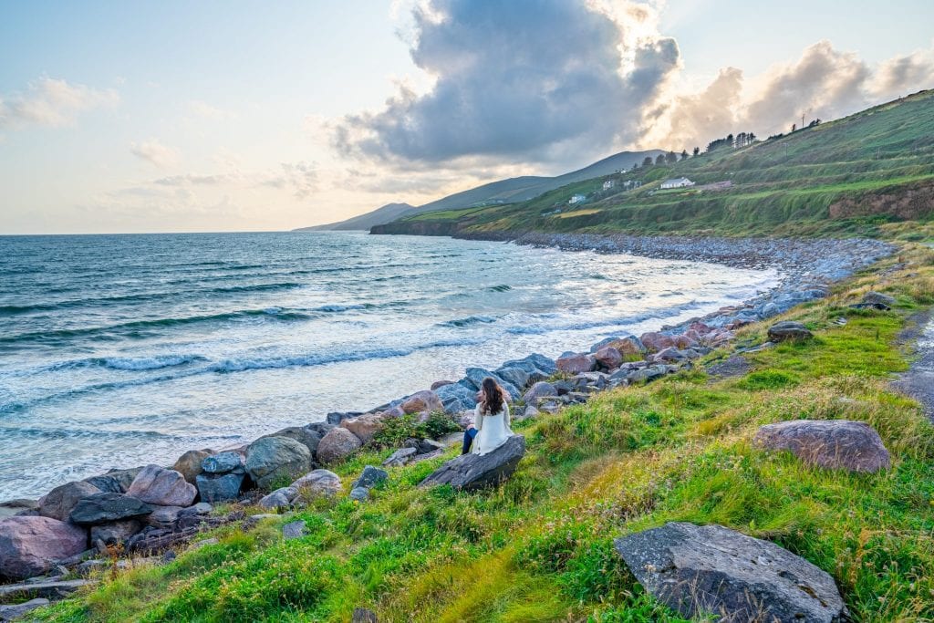 Kate Storm in a cream cardigan near Inch Beach Ireland at sunset--this is an incredibly romantic place to visit on your Ireland honeymoon!