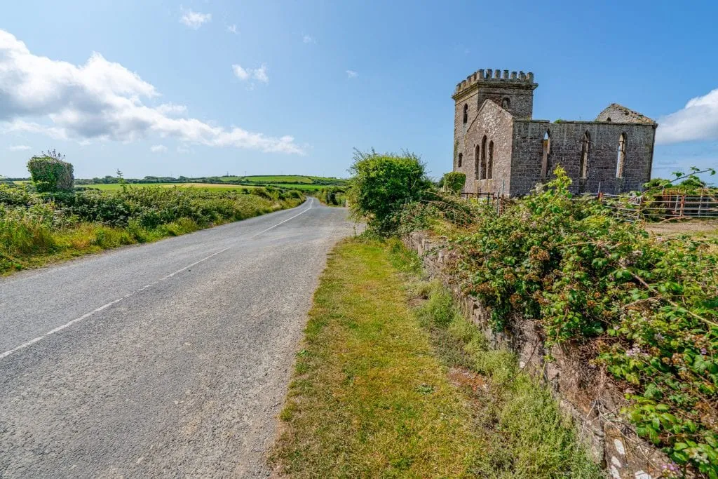 Empty road with castle to the right as seen on the Hook Peninsula, one of the best day trips from Dublin Ireland