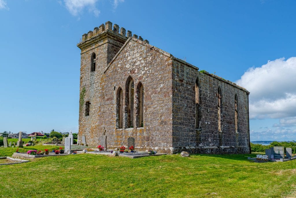 Abandoned castle in Ireland in County Wexford on a sunny day with abbey in the foreground--places like this are incredible to visit as part of an Ireland honeymoon!