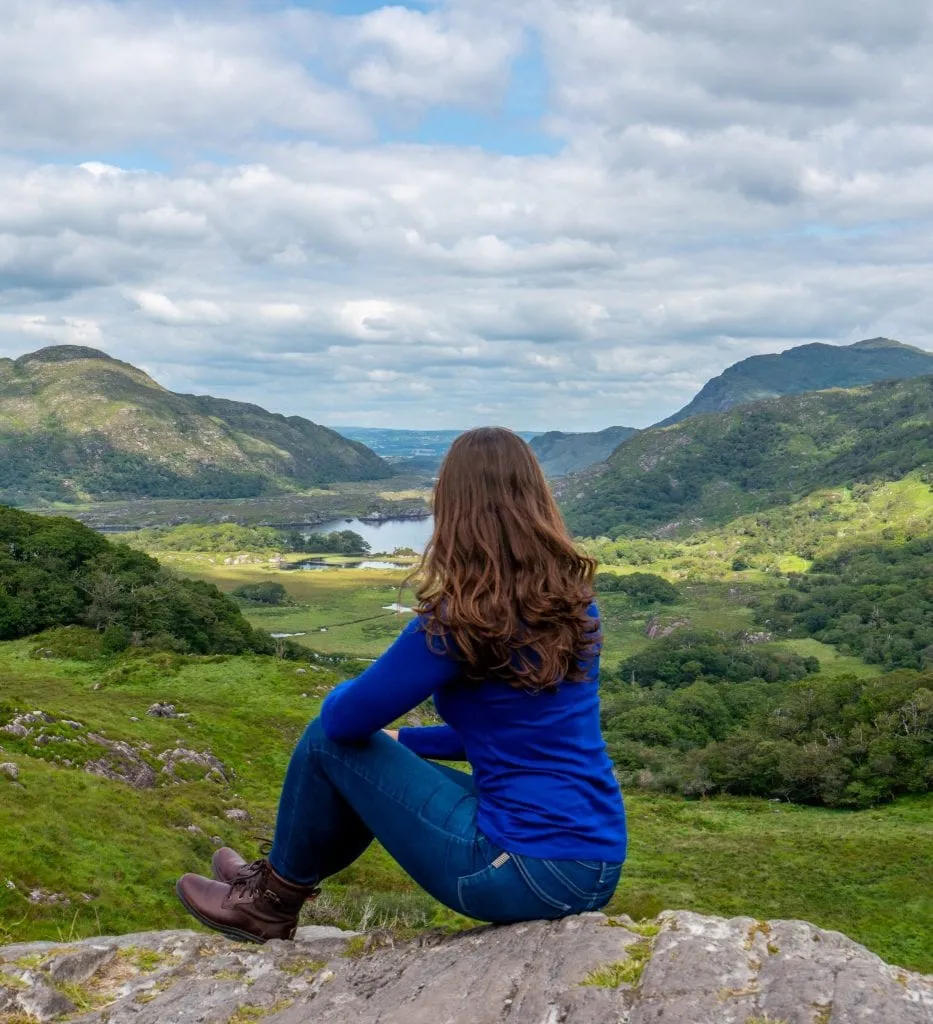 Kate Storm overlooking Ladies View in Killarney National Park, wearing a blue shirt and looking away from the camera. Views like this are perfect for visiting during your honeymoon in Ireland!