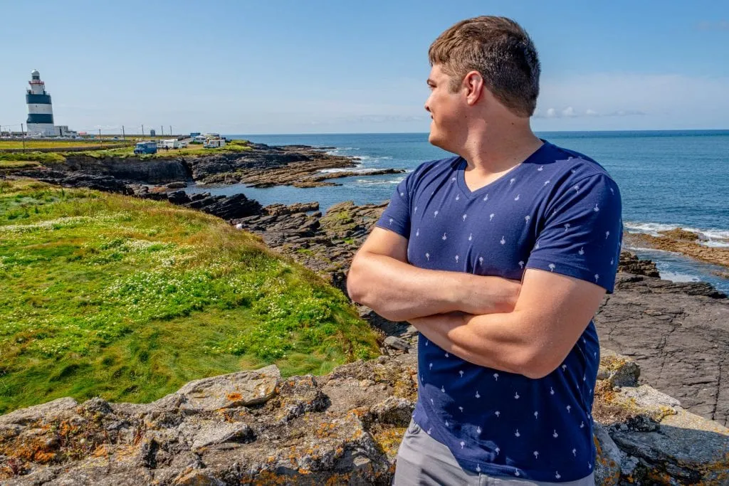 Jeremy Storm in a blue shirt looking at Hook Lighthouse in County Wexford Ireland