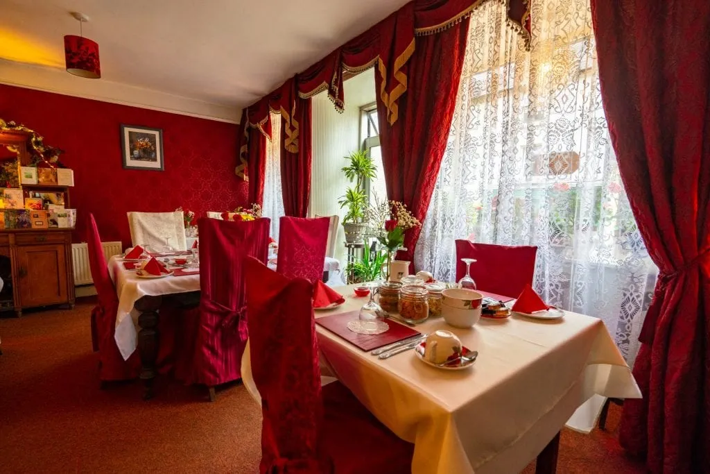 Breakfast room at Inishross House with red chairs and red curtains--definitely a cozy place to stay as part of your honeymoon in Ireland!