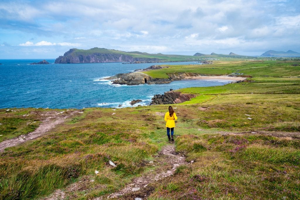 Kate Storm on Slea Head Drive on the Dingle Peninsula in Ireland, facing away from the camera and wearing a yellow raincoat.