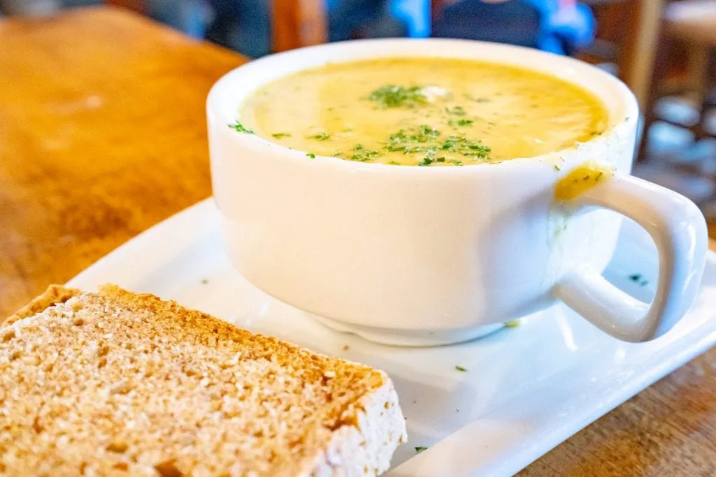 cup of soup served in a white bowl in Ireland with a slice of Irish brown bread in the foreground