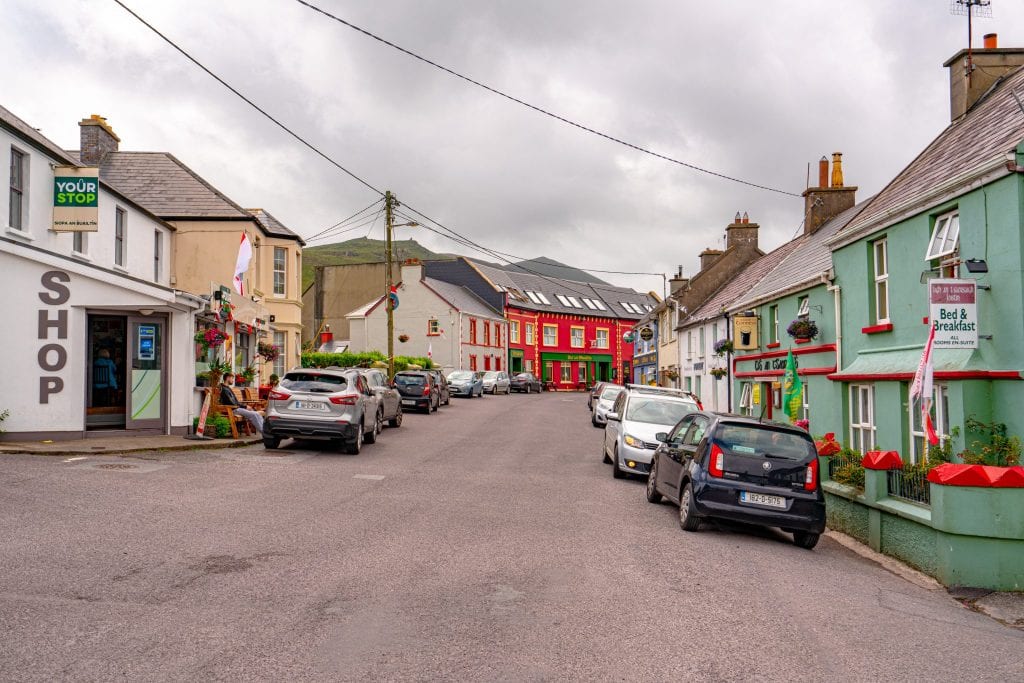 Main street in Ballyferriter Village with colorful buildings on either side and a cloudy sky