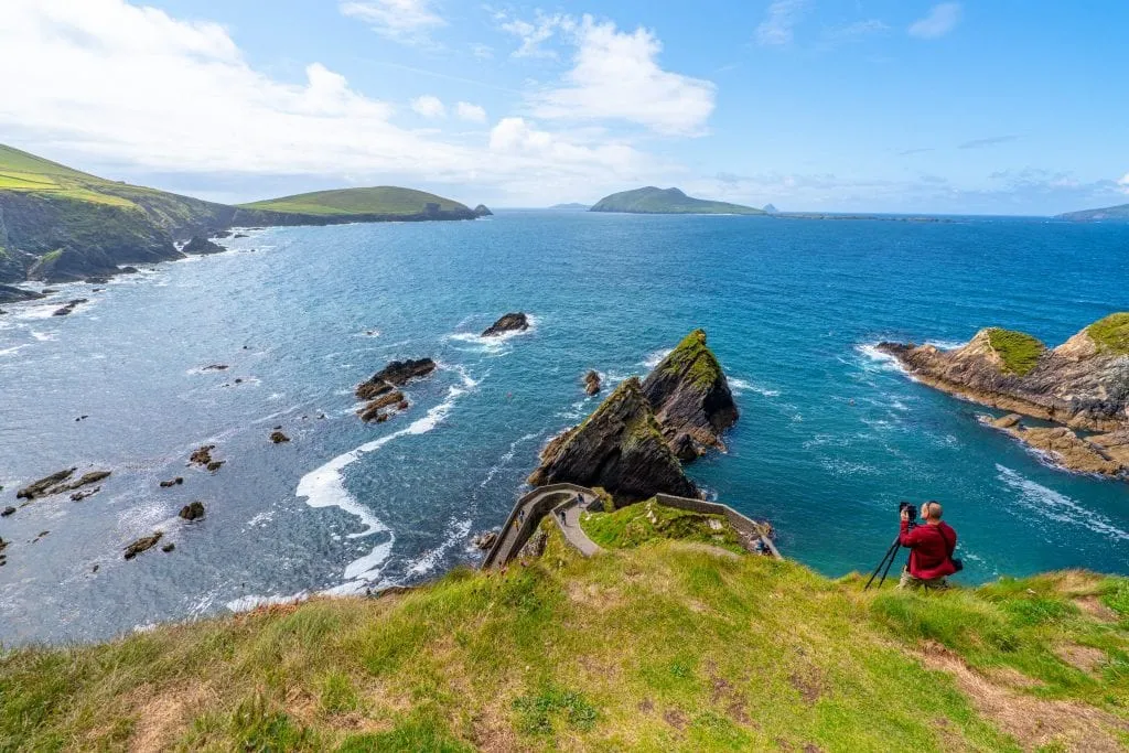 Dunquin Pier on Slea Head Drive, an unmissable place to see on a 10 days in Ireland itinerary. There's a photographer with a tripod and red jacket on the right side of the photo.