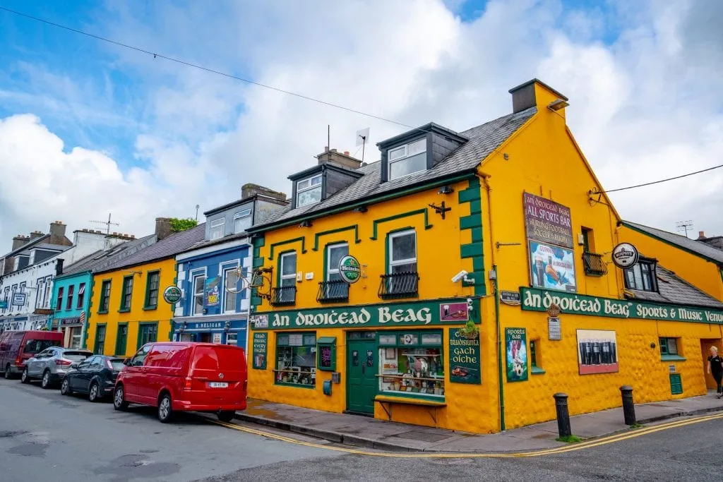 Colorful street in Dingle Ireland with a bright yellow building. Dingle is the starting point for Slea Head Drive.