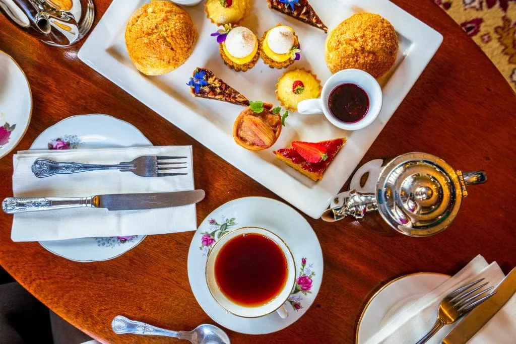 Photo of an afternoon tea in Ireland taken from above, with a collection of sweets, a silver teapot, and a cup of tea