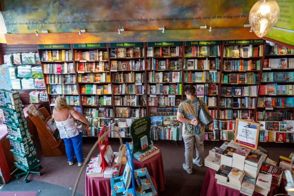 Bookstore in Ireland as shot facing a line of bookcases on the back wall. A few people are browsing at the shelves