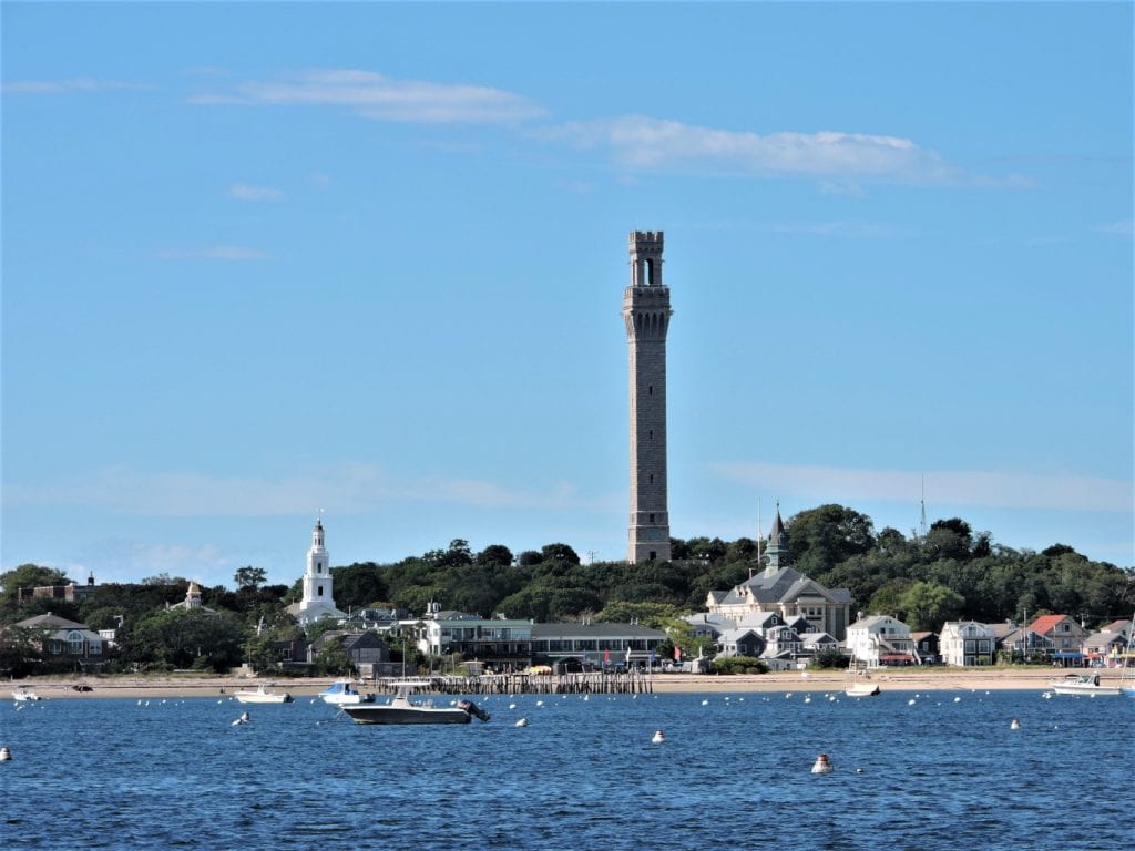 Provincetown MA from the water, with boats in the foreground. Located on Cape Cod, it's definitely one of the best places to visit in New England!