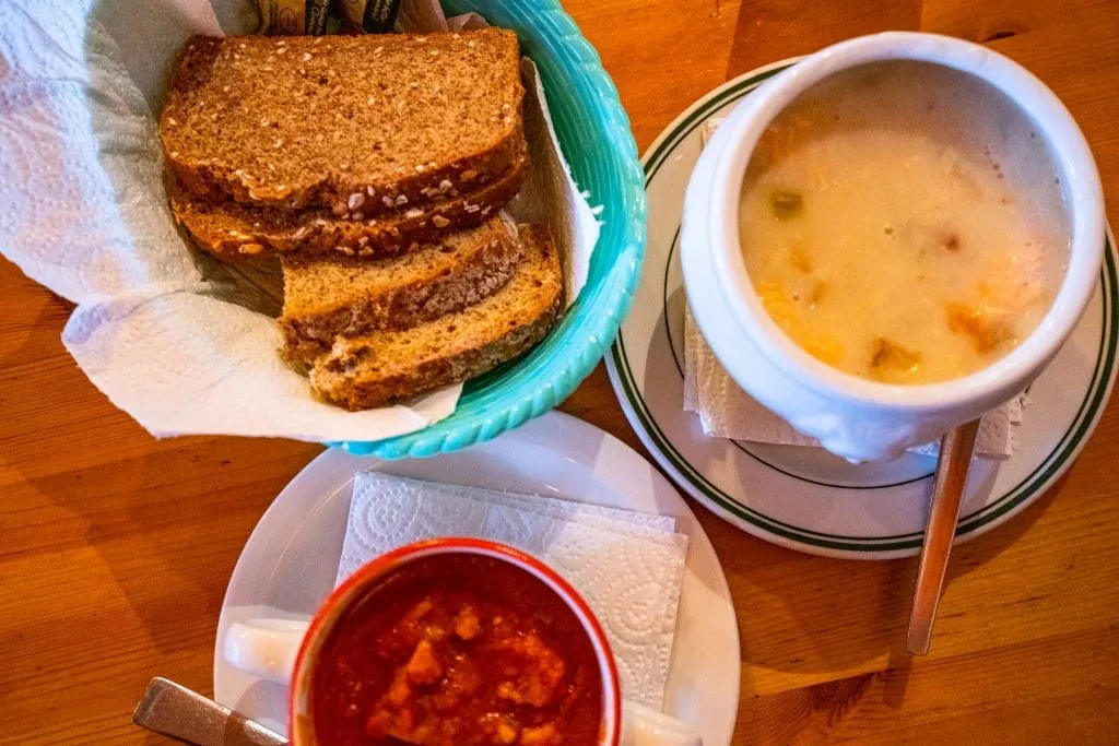 Irish brown bread with two cups of soup next to it, one of the best things to try when deciding what to eat in Ireland
