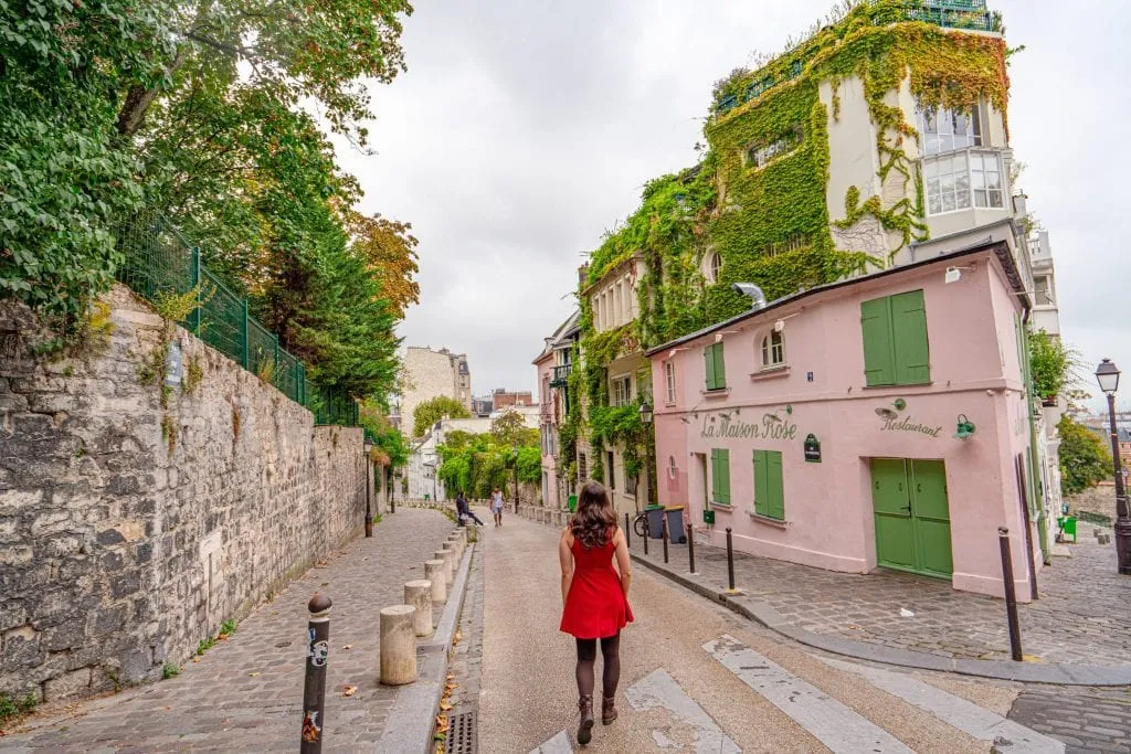 kate storm in a red dress in from of la maison rose montmartre pink house