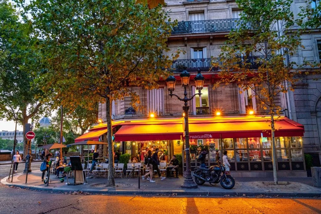 Cozy sidewalk bistro on an evening in Paris, with outdoor tables lit by lamps