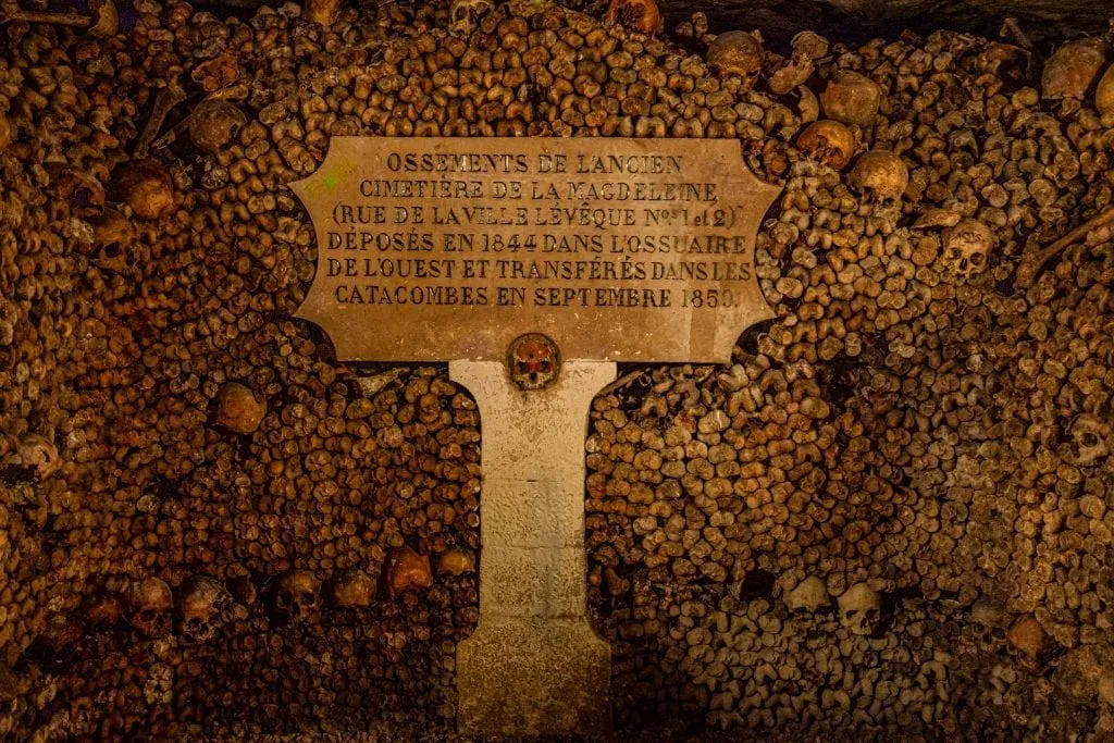 Stack of bones with a grave marker in the Paris catacombs