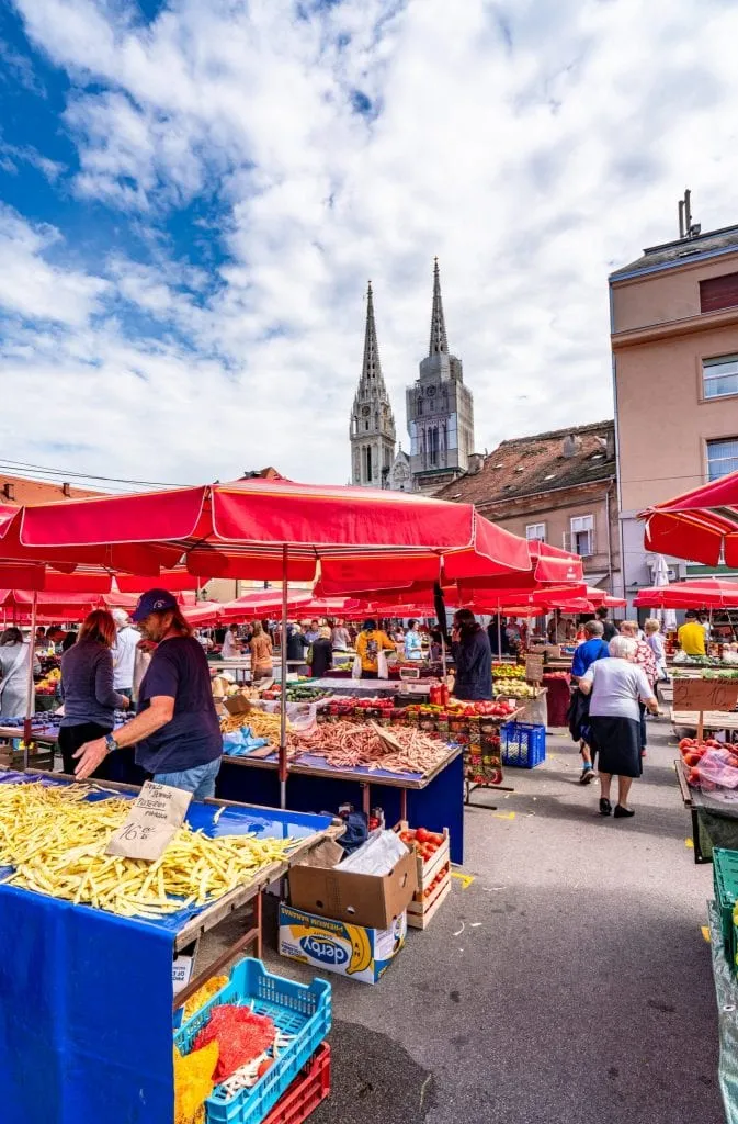 food stand at dolac market when visiting zagreb croatia, with red umbrella and cathedral visible