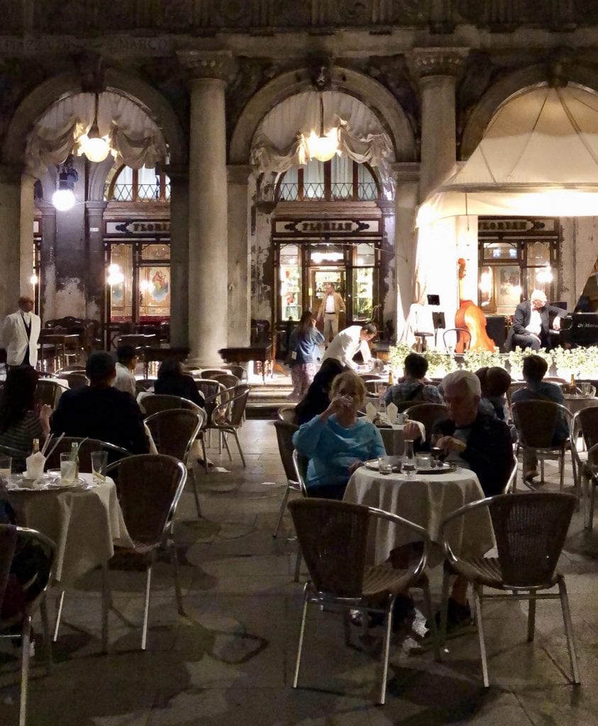 Caffe Florian at night, with patrons sitting at tables in front of the cafe.