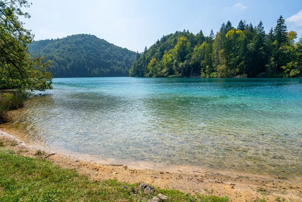 Small beach in Plitvice Lakes National Park Croatia with turquoise lake taking up most of the frame