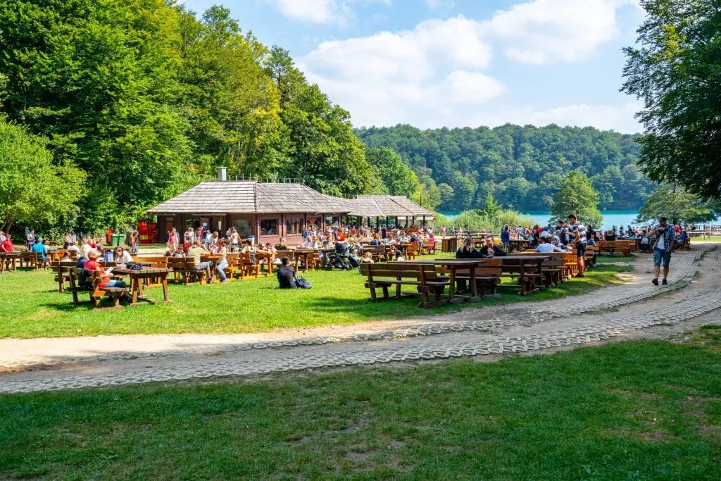 Restaurant inside Plitvice Lakes Park as seen from a distance, with picnic tables visible across the field.