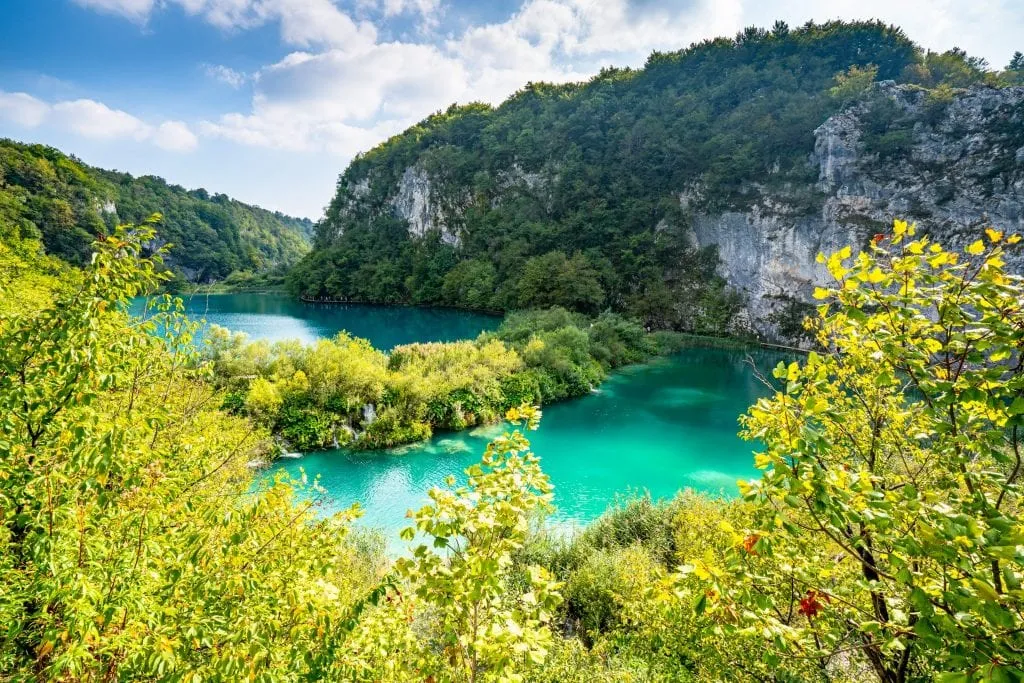 Bright turquoise Plitvice Lakes as seen from above with karst cliffs visible in the distance