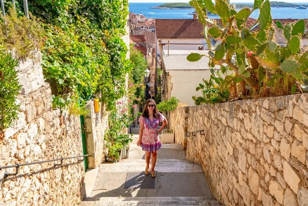 Kate Storm in a pink dress standing on a small stone street in Hvar Croatia