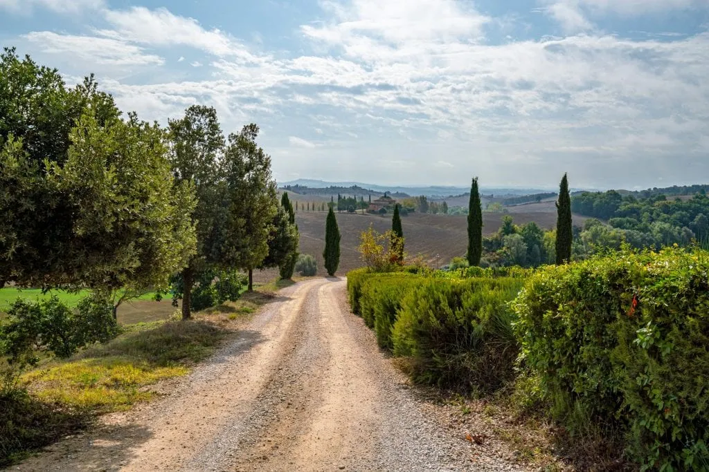 Dirt road in Tuscany with cypress trees visible in the distance--you can detour to views like these quite easily when driving from Rome to Florence