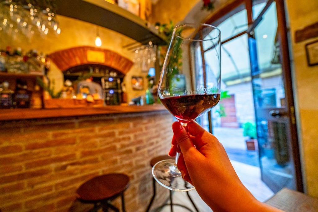 hand holding up a glass of vino di nobile montepulciano italy wine bar