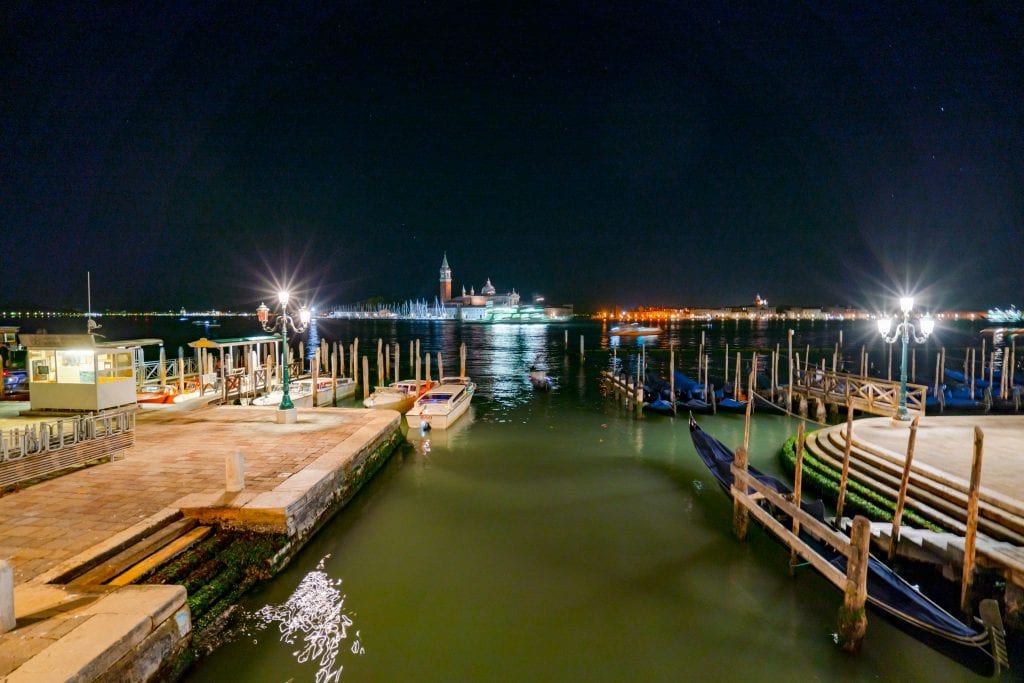 Photo of Venetian Lagoon from Riva degli Schiavoni at night, with parked gondolas visible--when deciding what to do in Venice at night, don't forget about the joy of taking a walk!