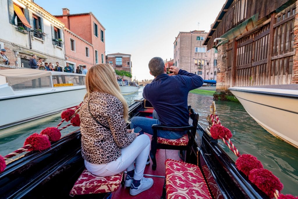 A man and a woman on a gondola ride in Venice, the man is taking photos