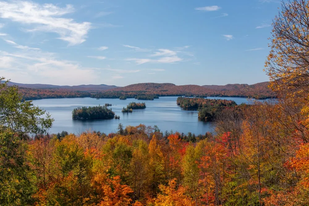 Overview in Adriondacks New York showing fall foliage and a lake in the distance. The Adriondacks are one of the best east coast USA road trips!