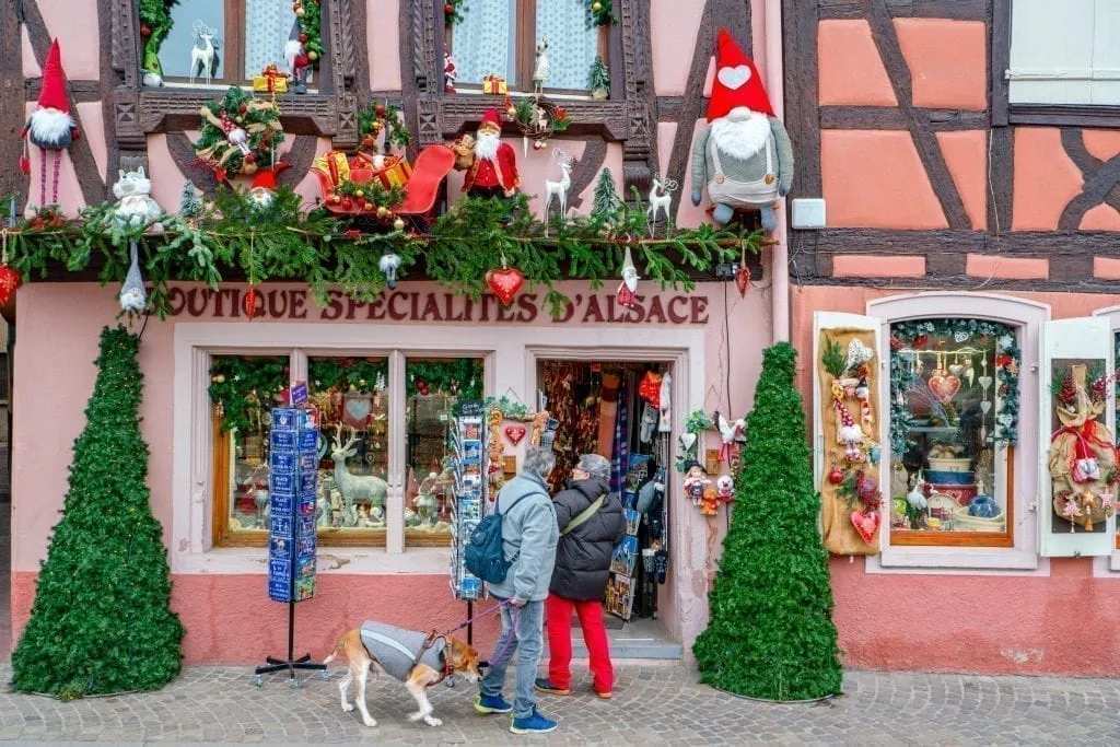 Couple shopping in front of a pink storefront in Colmar that is decoarted for Christmas in Colmar
