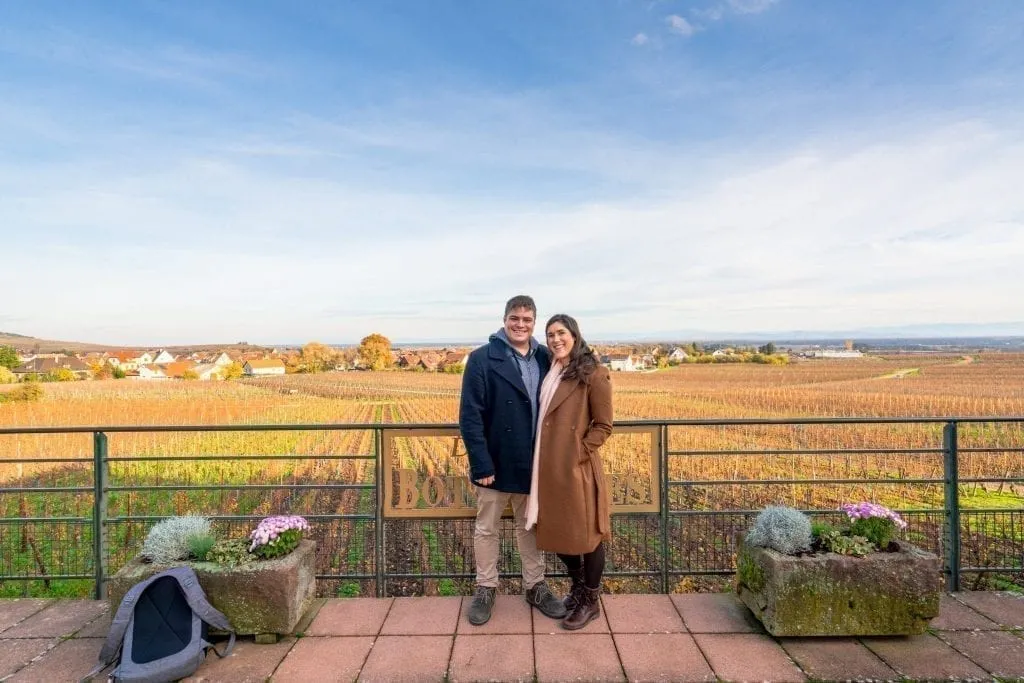 Jeremy Storm and Kate Storm at a winery on the Alsace Wine Route in the winter with grape vines visible behind them