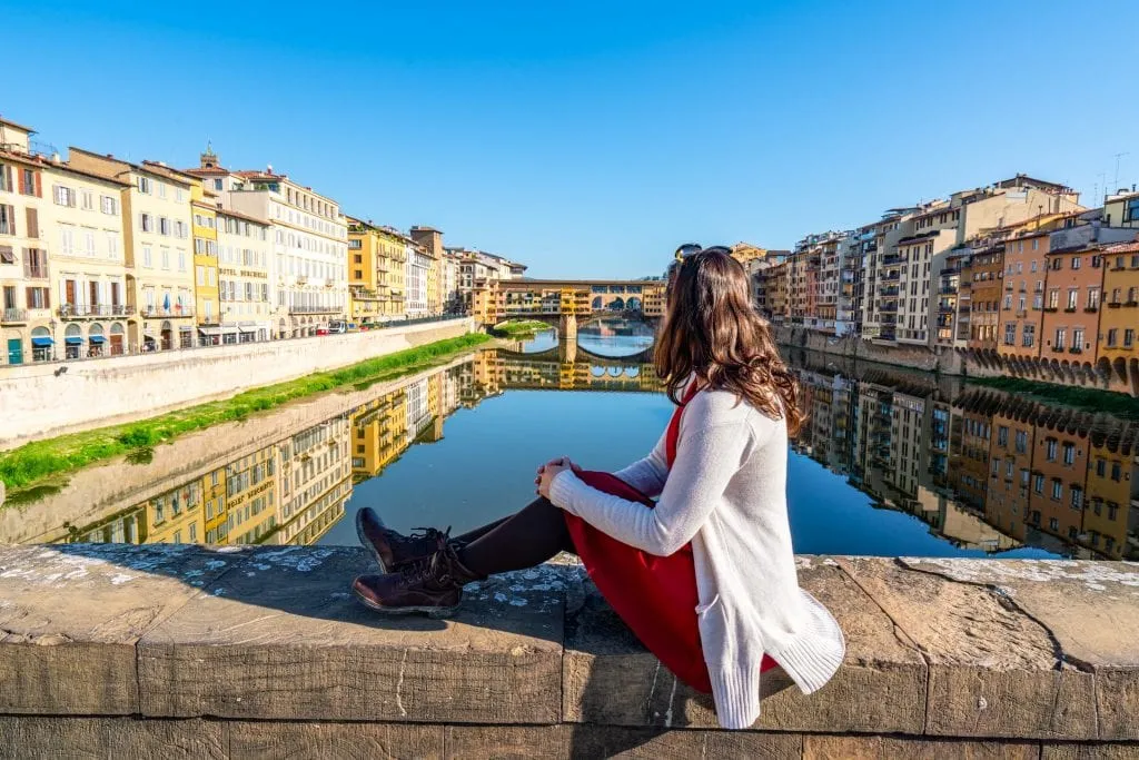 Kate Storm in a red dress overlooking the Ponte Vecchio in Florence Italy