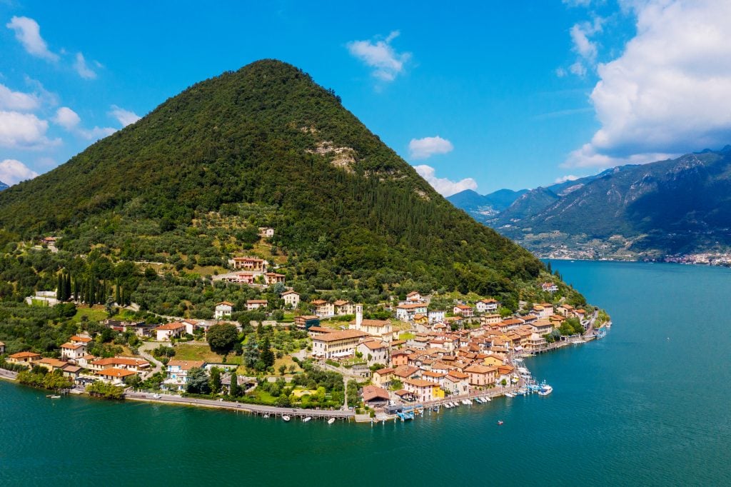 aerial view of Peschiera Maraglio with a large hill behind it and lake iseo in the foreground