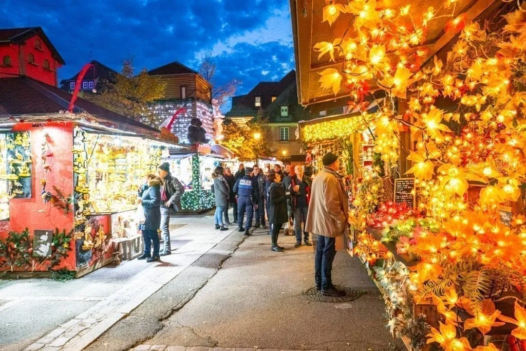 people shopping at a christmas market in colmar, one of the best christmas villages in europe