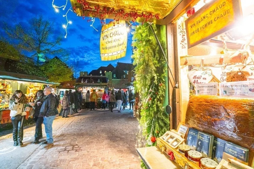 Christmas market stall open in Colmar at night with dark blue sky visible in the background