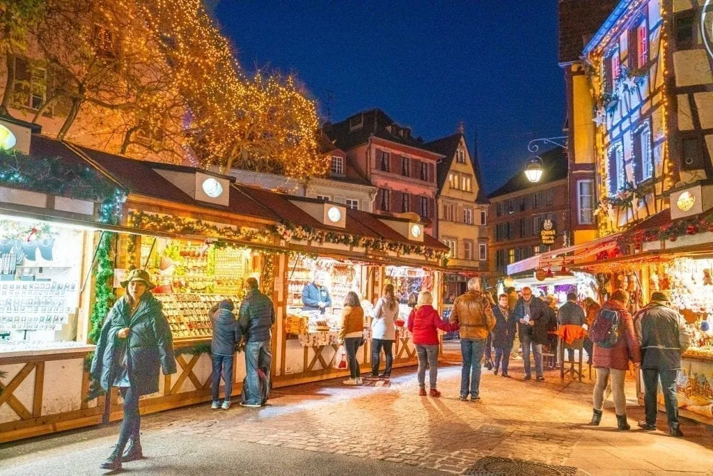Colmar Christmas market at night with shoppers in front of several stalls