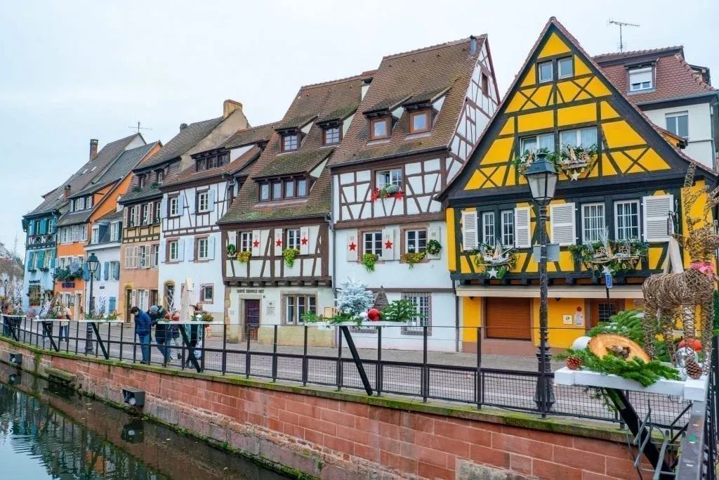 Row of houses in La Petite Venise with a yellow house the most prominent. Located in Colmar France