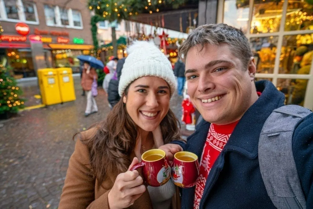 kate storm and jeremy storm with mugs of gluhwein in cologne on a europe christmas itinerary
