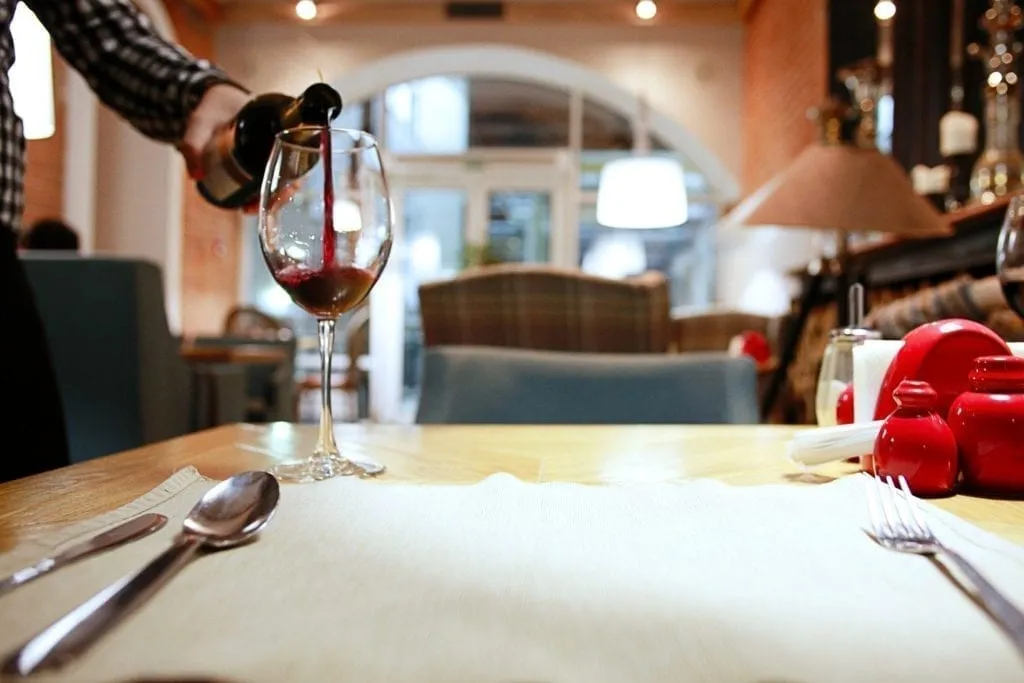 glass of red wine being poured in a restaurant in Paris at night