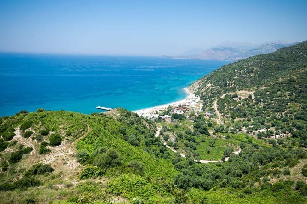 Albanian Riviera as seen from above with a winding mountain road in the foreground and the bright sea in the background