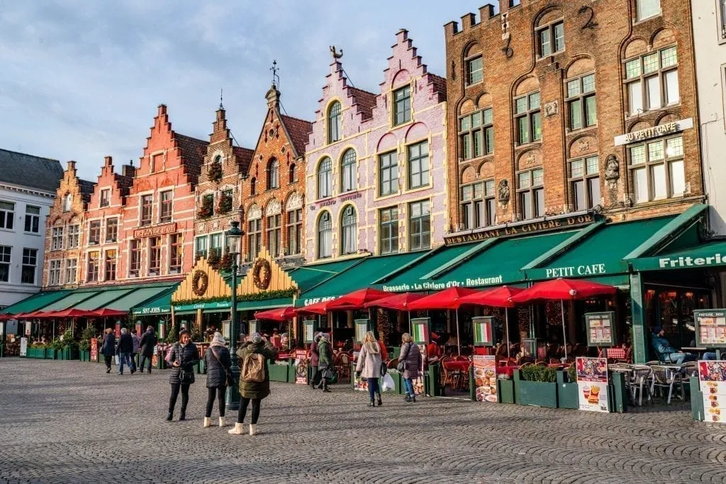 people walking through market square during one day bruges itinerary