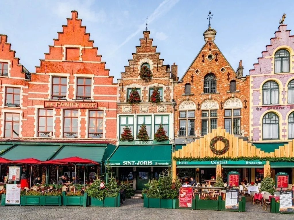 Grote Markt ở Bruges Bỉ với 4 tòa nhà đầy màu sắc hiện rõ với mái hiên xanh phía trước - một điểm dừng chân không thể bỏ qua trong hành trình 3 ngày ở Bỉ của bạn