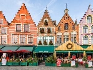 Grote Markt in Bruges Belgium with 4 colorful buildings visible with green awnings out front--an essential stop during your 3 day Belgium itinerary