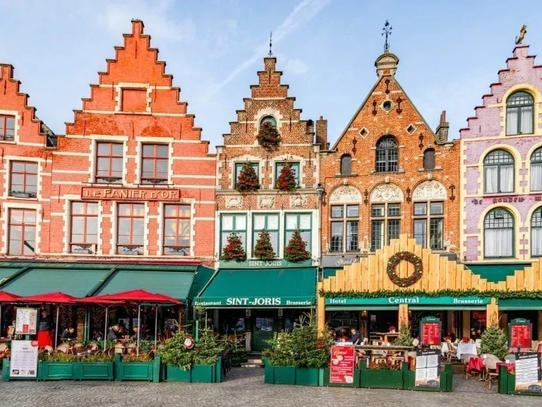 Grote Markt in Bruges Belgium with 4 colorful buildings visible with green awnings out front--an essential stop during your 3 day Belgium itinerary
