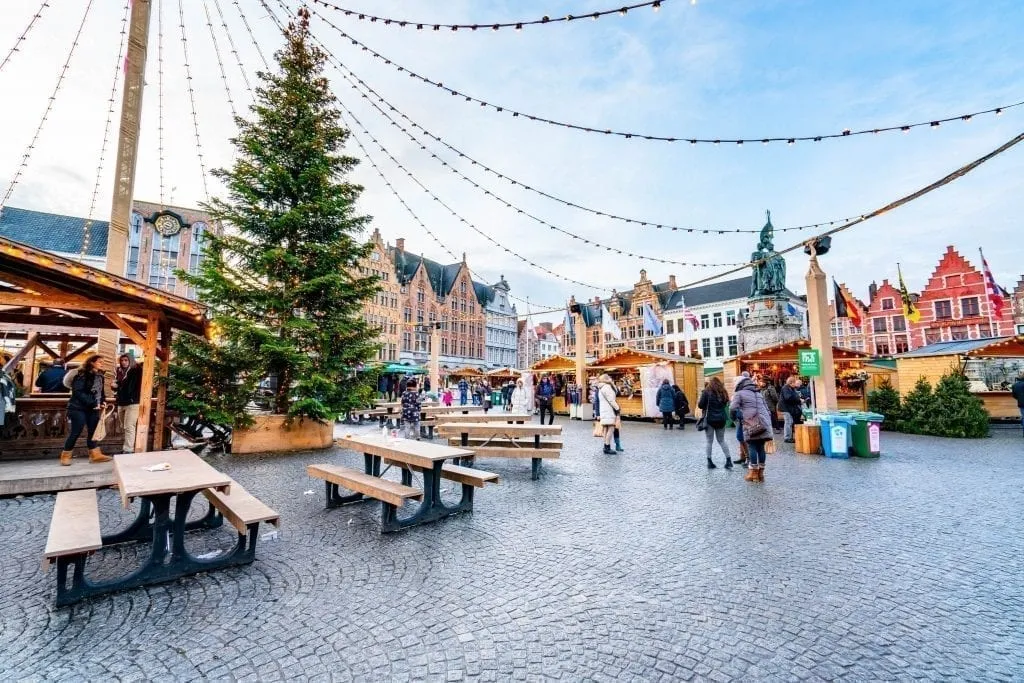 One of the best Christmas markets in Europe in Bruges Belgiu with a large tree on the left side of the photo