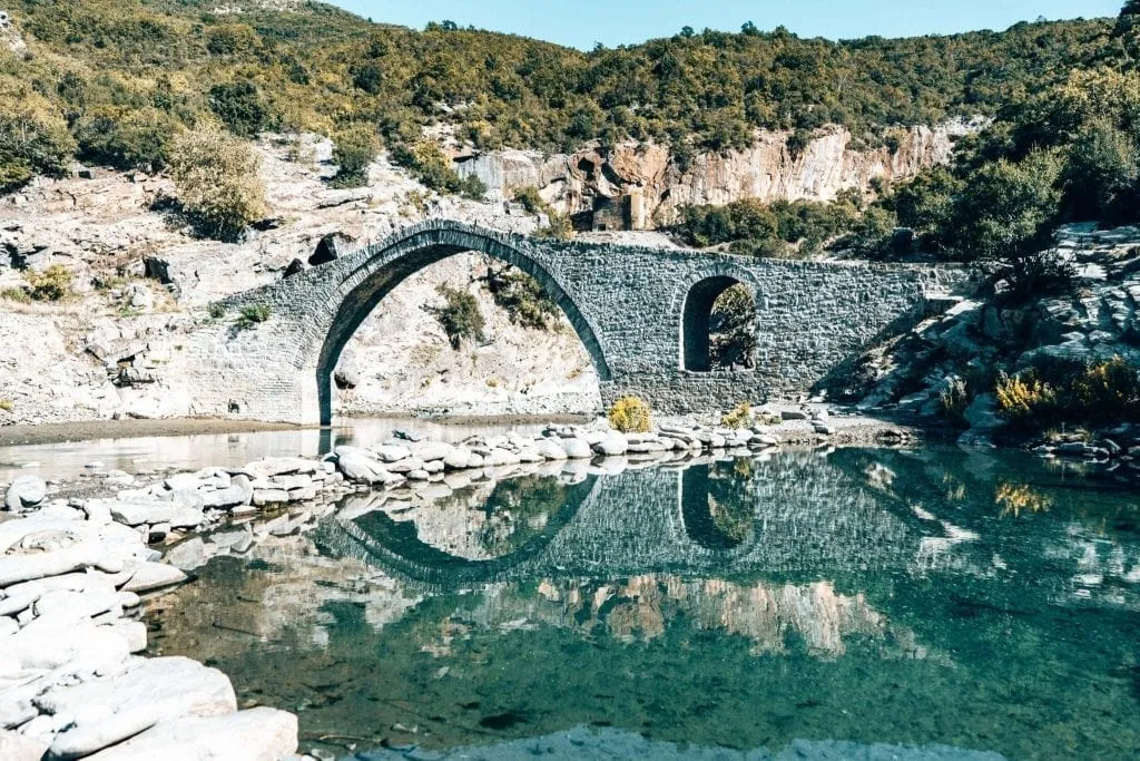 Stone footbridge built over a bright blue river, as seen on an Albanian road trip