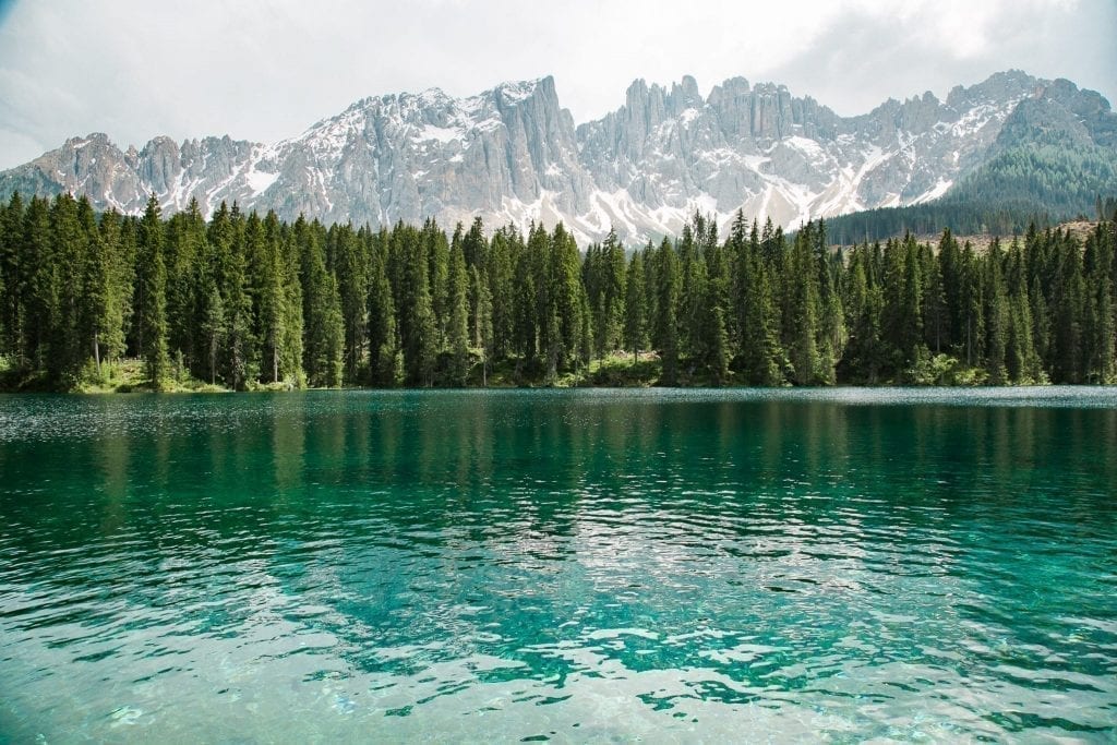 Photo of Italian Dolomites on a cloudy day with a bright lake in the foreground. The Italian Dolomites are one of the best additions to a Europe road trip itinerary!